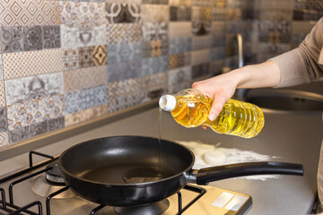 The girl pours oil onto the frying pan