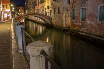 Fototapeta na wymiar Quiet and calm still life small stone bridge spanning canal by night, Venice, Italy 