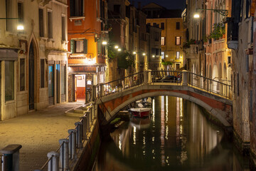 Fototapeta na wymiar Quiet and calm still life small stone bridge spanning canal by night, Venice, Italy 