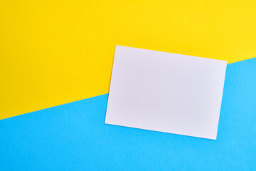 Blank white card isolated on blue and yellow background. Place for text. Mock up greeting card. Form