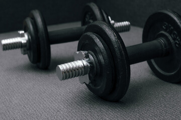 Naklejka na ściany i meble Fitness background. Two 10 kg dumbbells on a gray mat. Sports concept - gray mat, two black dumbbells 10 kg