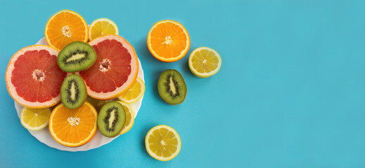 Chopped tropical fruits on the white plate on the blue background.Top view. Copy space.