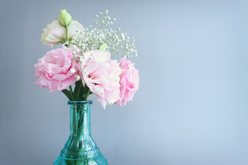 Top view image of delicate lisianthus flowers in the blue vase over pastel background