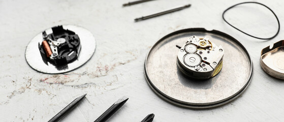 Broken watch and tools for repair on light background