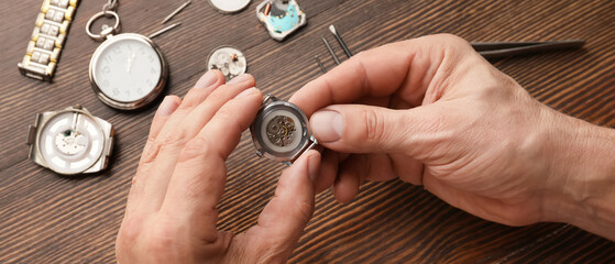 Male clock maker repairing broken watch at table