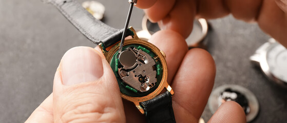 Male clock maker repairing broken watch at table, closeup