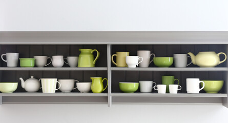 Shelves with clean dishes hanging on white wall in kitchen