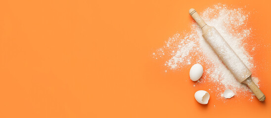 Fototapeta Rolling pin, flour and eggs on orange background with space for text obraz