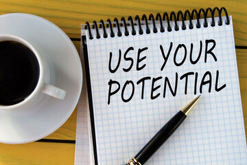 USE YOUR POTENTIAL - words on a white sheet on a yellow wooden background with a pen and a cup of coffee