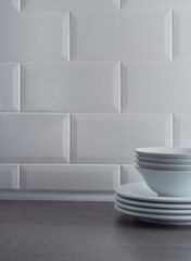 White plates on grey textured countertop on a white tile wall background. Table setting concept.
