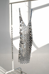 Chain mail dress on a rail for clothes in a light studio interior. 