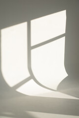 White studio cyclorama illuminated by sunlight with window shadow. White wall, minimalistic interior. 
