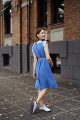 Happy pregnant woman chilling and having fun while walking in the city in a midi blue vintage dress. Happiness all around