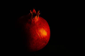 Ripe pomegranate fruit on a black background close up