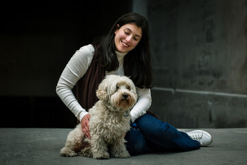 Girl sitting on the floor with her dog in the city. Happy girl with her dog. white furry dog