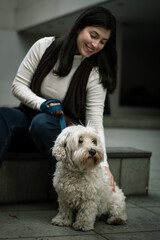 Smiling woman petting her dog in the city. Dog looking into the distance with its owner