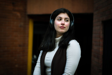 Thoughtful woman listening to music in the city. White woman with headphones listening to music. relaxed woman