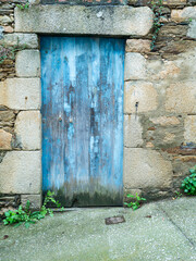 Puerta de madera pintada de azul en fachada de piedra antigua, en el pueblo de O Porto do...