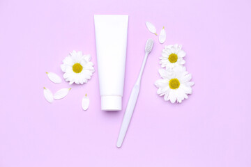 Composition with tube of toothpaste, toothbrush and chamomile flowers on lilac background