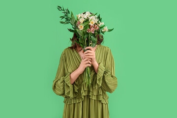 Young woman in dress with alstroemeria flowers on green background