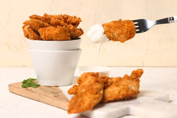 Fork with tasty nuggets on light background, closeup