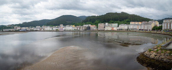 Vista panorámica de la costa en la ría de Viveiro ,Lugo, con las montañas verdes al fondo, casas en la orilla y marea baja, en Galicia, verano de 2021