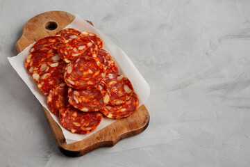 Spanish chorizo salami sausage on a rustic wooden board on a gray background, side view. Copy space.
