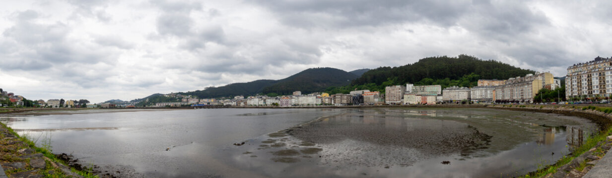 Views of the estuary of the town of Viveiro in Lugo, Galicia, with sea water lapping the sand on the shore at low tide on a cloudy day in the summer of 2021, Spain.
