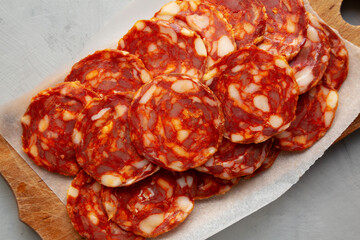 Spanish chorizo salami sausage on a rustic wooden board on a gray background, top view. Flat lay, overhead, from above.