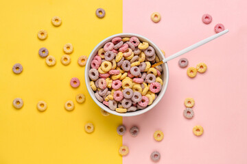 Bowl of colorful cereal rings on yellow and pink background