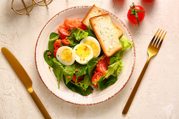 Plate of delicious salad with boiled eggs and salmon on white grunge background