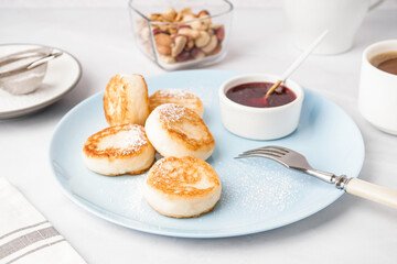 Plate with tasty cottage cheese pancakes and strawberry jam on light background
