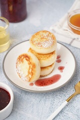 Plate with tasty cottage cheese pancakes on light table, closeup