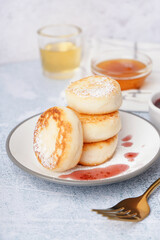 Plate with delicious cottage cheese pancakes on light background, closeup