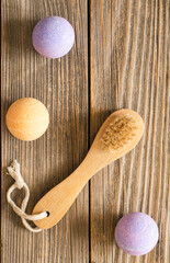 Obraz na płótnie Canvas Spa composition with wooden massage brush and colorful bath bombs on wooden background, top view.