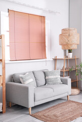 Grey sofa with cushions in interior of cozy living room