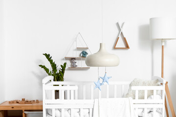 Interior of light children's bedroom with baby crib and shelves