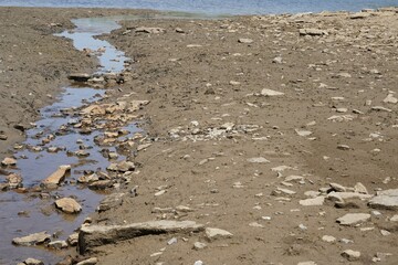 Tributary stream of a lake on the dried up bottom of soil. A sign of water scarcity that diminishes...