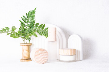 Fototapeta na wymiar Eco friendly natural cosmetic products such as cream, loton, serum or balm on white stone background with clay geometric decorations and fern leaves. Skin care concept.