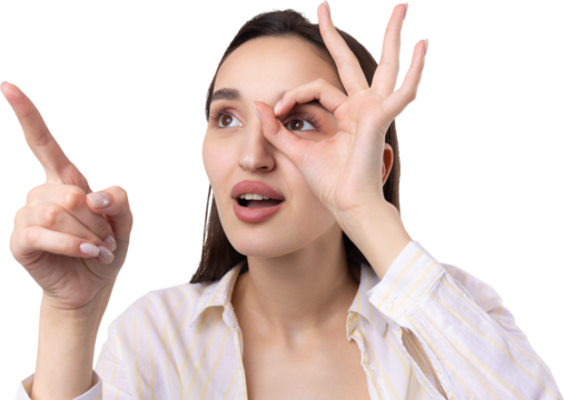 Close up portrait of attractive quirky young woman making binoculars with hands showing ok gesture on white studio background.