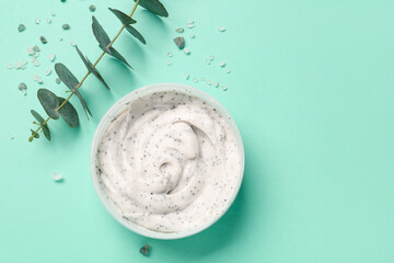 Jar of body scrub and eucalyptus branch on color background
