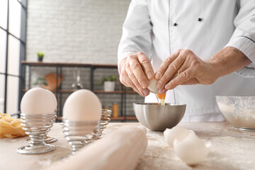 Male chef making dough for pasta at table in kitchen, closeup