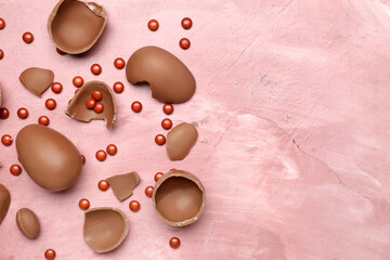 Candies and pieces of chocolate Easter eggs on pink background