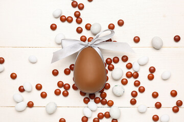 Candies and chocolate Easter egg tied with ribbon on white wooden background