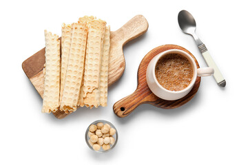 Board with delicious wafer rolls, hazelnuts and cup of coffee on grey background