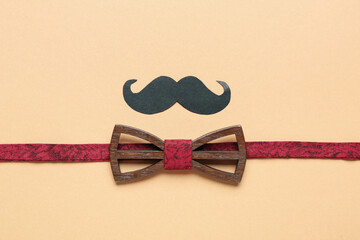 Composition with stylish wooden bow tie and paper mustache on color background