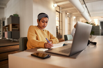 Businesswoman writing notes at an office desk