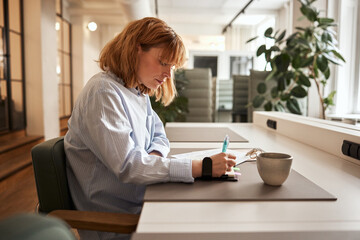 Businesswoman writing in a notebook at work