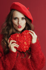 stylish woman in red sweater and beret sending kiss