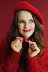 smiling stylish woman in red sweater and beret with candy
